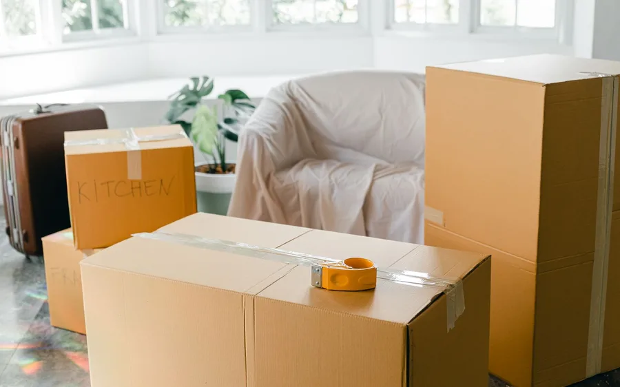 Packed moving boxes labeled Kitchen and Fragile in an empty, sunlit room